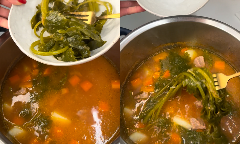 Two images side by side show someone adding leafy greens from a bowl into a pot of simmering soup with chunks of meat, carrots, and potatoes. The soup has a reddish broth and is being stirred with a yellow fork.