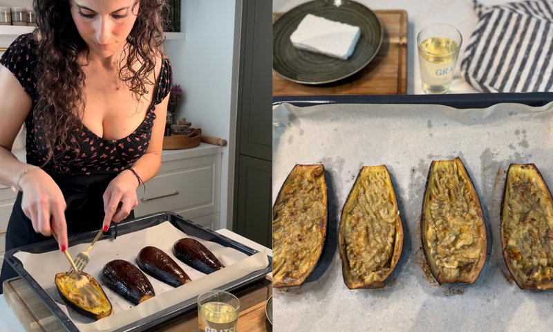 A woman uses a fork to score halved, roasted eggplants on a baking tray. Insets show a plate with feta, a glass of white wine, and baked eggplants with golden, scored flesh on parchment paper.