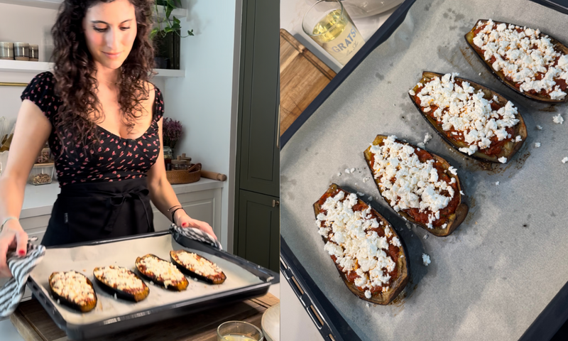 A woman in a kitchen places a tray of four stuffed eggplant halves topped with crumbled cheese onto a counter; a close-up shows the eggplants on parchment paper before baking.