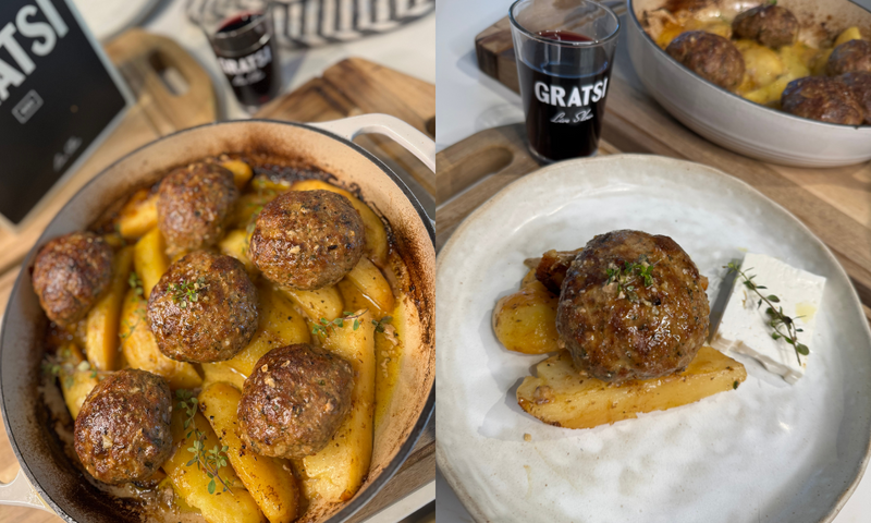 A baked dish with meatballs and golden potato wedges garnished with herbs, served on a plate with feta cheese and a glass of red wine labeled GRATSI in the background.