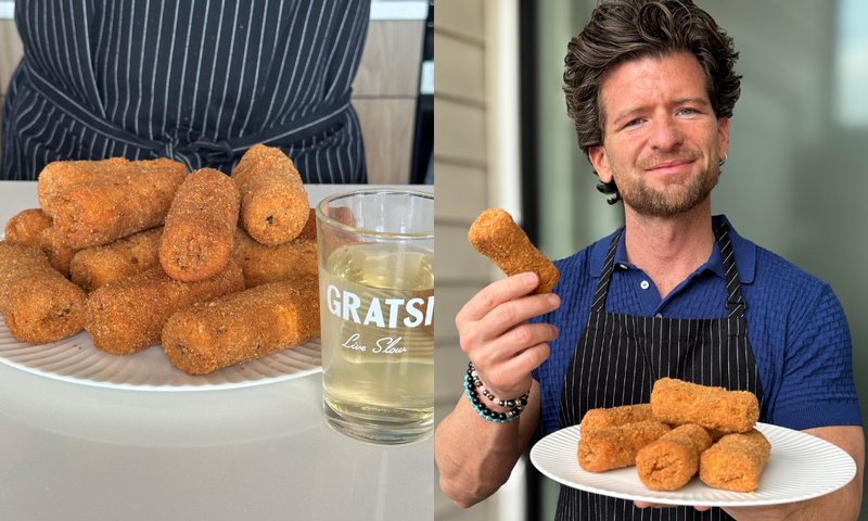 A man in a striped apron and blue shirt holds a plate of breaded croquettes. The left side of the image shows a close-up of the croquettes and a glass of clear drink on a white plate.