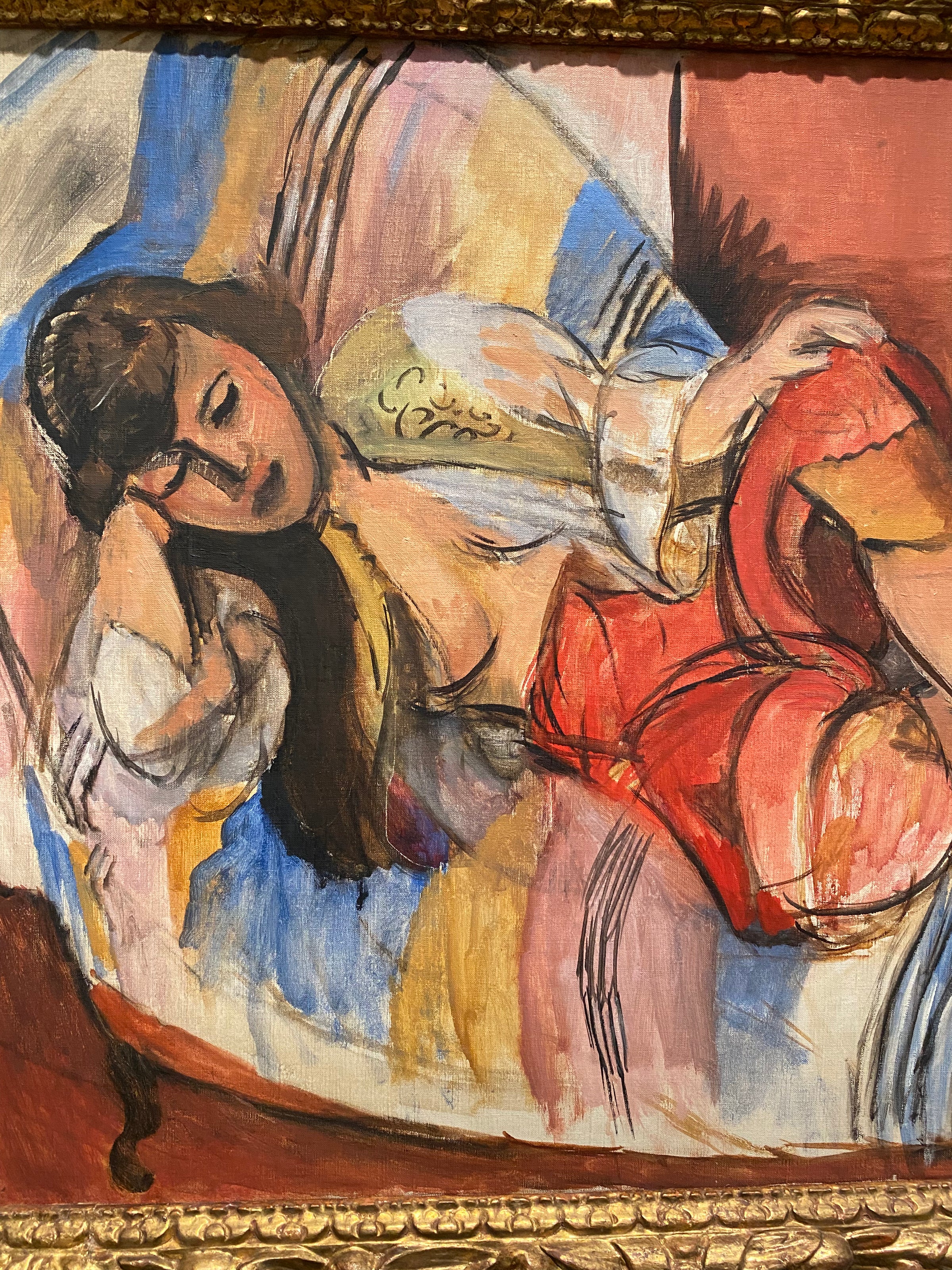 A painting of a woman with long brown hair reclining on a colorful striped couch, wearing a white blouse and a red skirt, with her eyes closed and arm resting on her head.