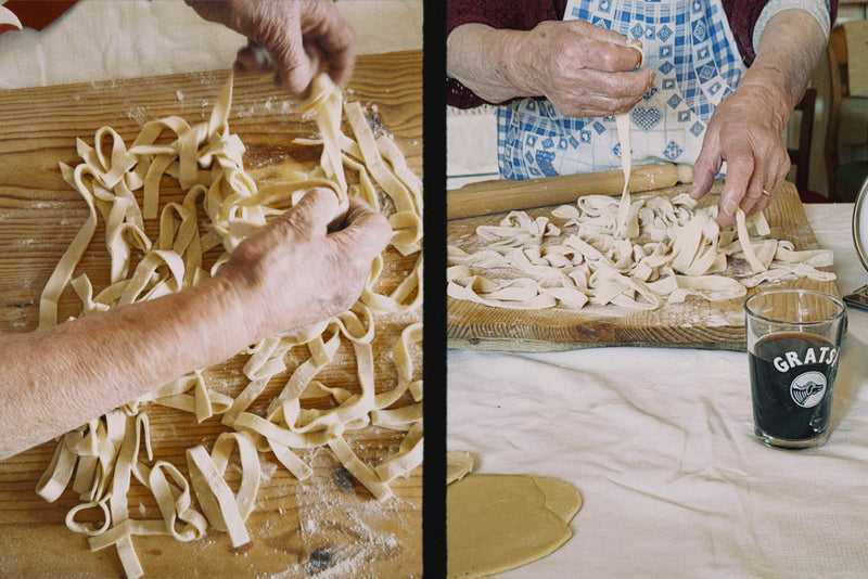 Two elderly hands prepare fresh pasta on a floured wooden surface, while another pair arranges noodles with a glass of red wine nearby. Both scenes show homemade pasta-making on a rustic table.