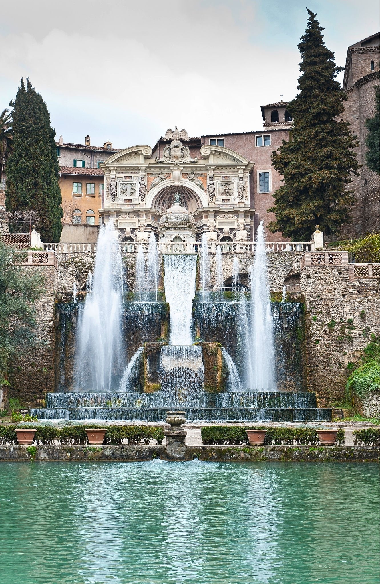 The image shows the ornate Fountain of Neptune with cascading water and classical statues at Villa d’Este in Tivoli, Italy, with greenery and historic buildings in the background.