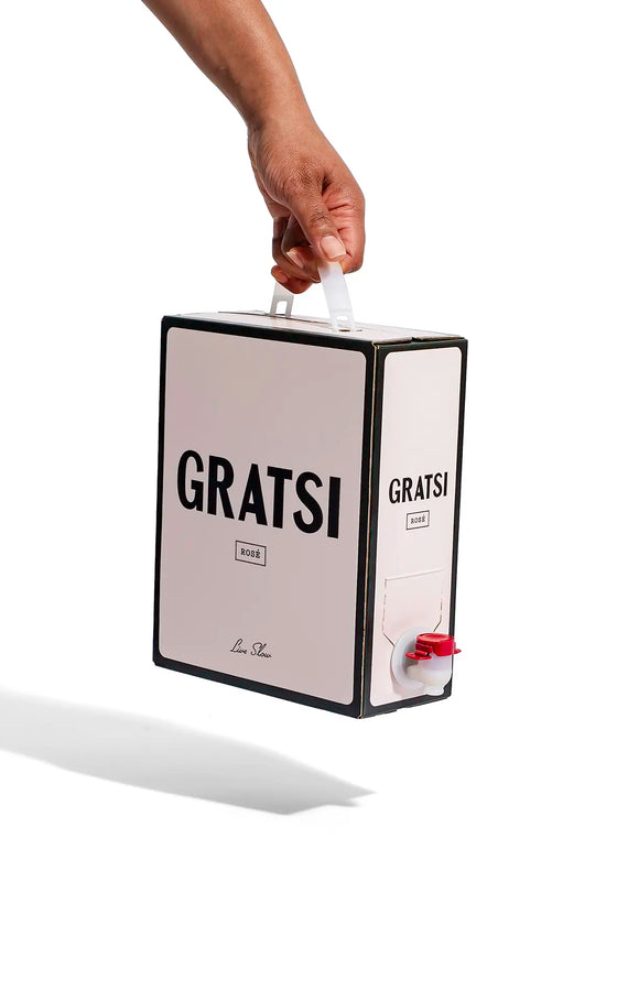 A hand holds a Gratsi Rosé Wine box with black text and a red spout against a white background, suggesting a refreshing, zero sugar experience.