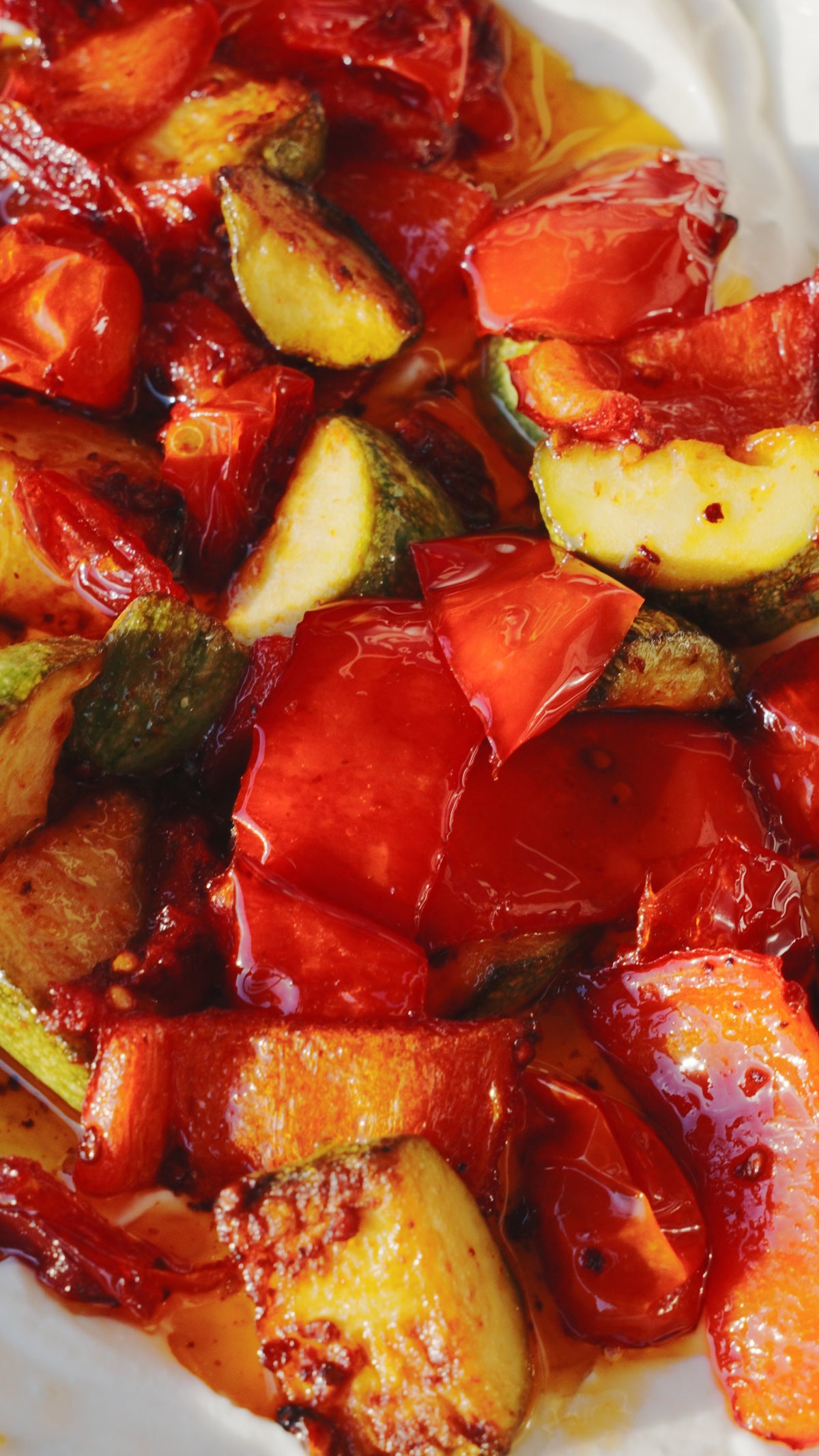 Roasted red peppers and zucchini slices coated in an oil-based sauce.