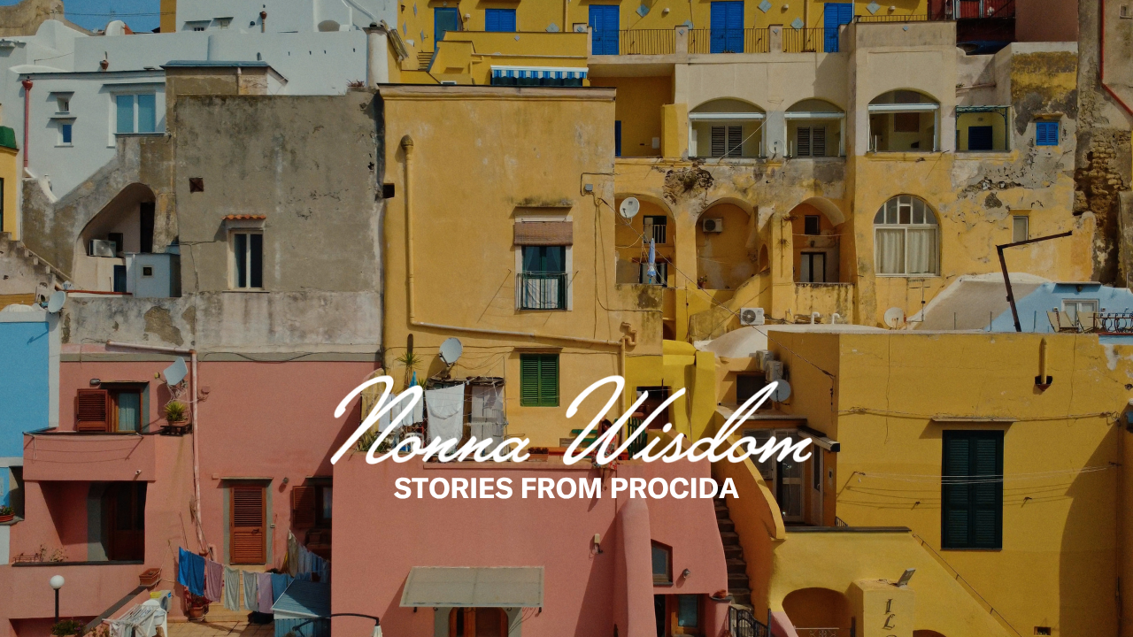Colorful, sunlit buildings in shades of yellow, pink, and blue line a hillside in Procida, Italy. The text “Nonna Wisdom: Stories from Procida” is overlaid in white script and bold type.