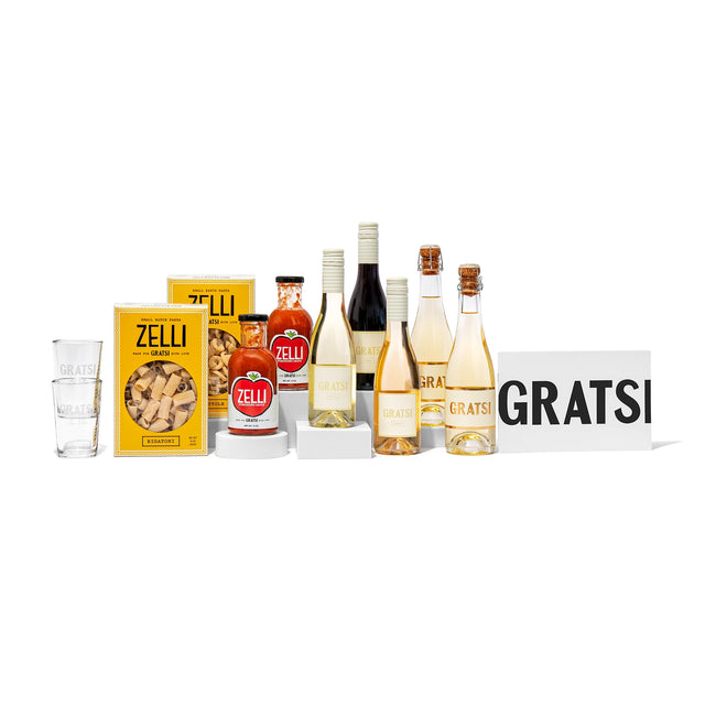 The Gratsi Date Night Bundle features zero-sugar wine, pasta, pasta sauce, a jar of spread, a glass, and product boxes—all beautifully arranged on a white background.