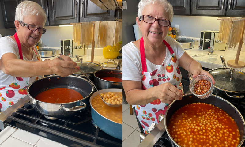 A smiling elderly woman in a tomato-print apron cooks chickpeas in tomato sauce on a stove, stirring the pot in one image and adding chili flakes in another. Uncooked spaghetti hangs nearby over the counter.