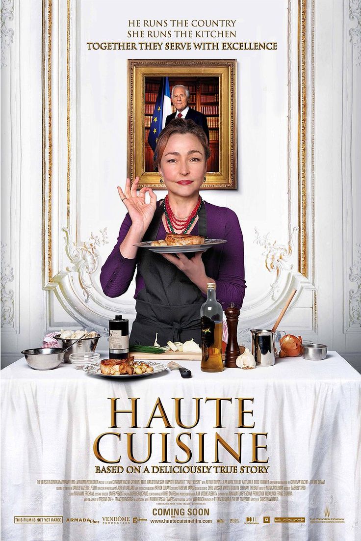 A woman in a chefs outfit holds a plate of food in front of a table set with dishes and ingredients. Behind her is a framed photo of a man in a suit. Text above and below promotes the film Haute Cuisine.