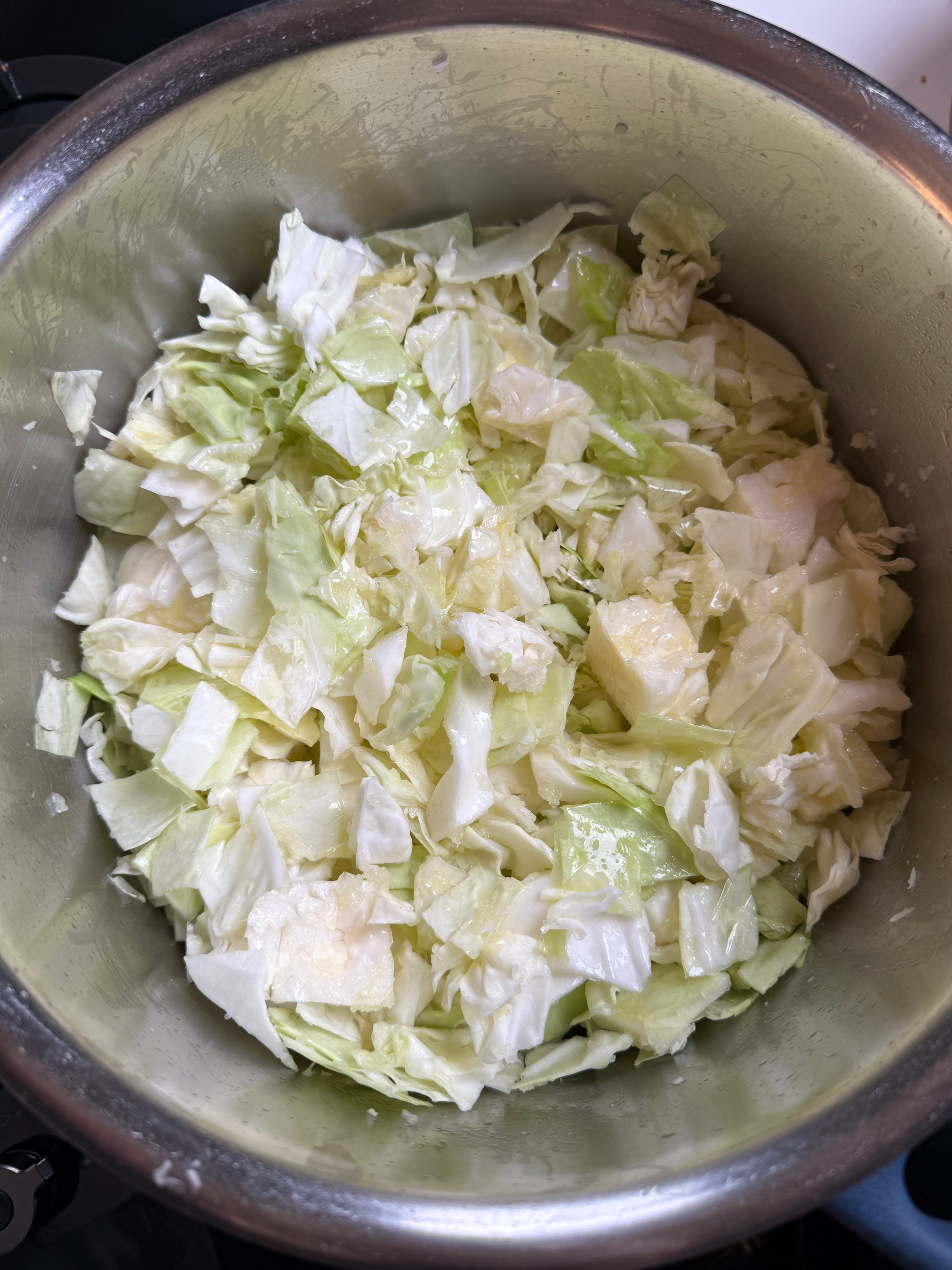 Chopped green cabbage pieces in a metal pot, ready for cooking.