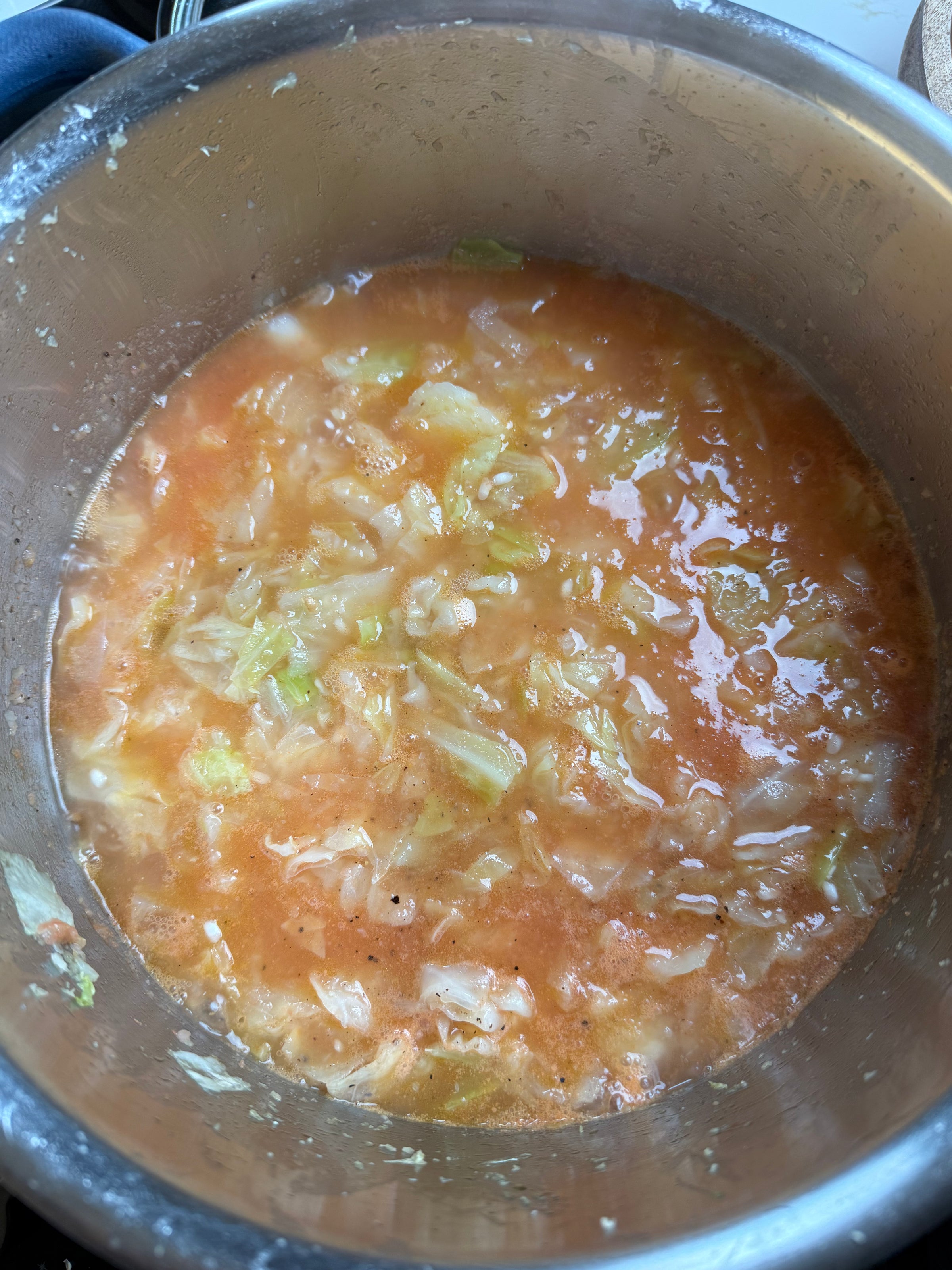 A pot of cabbage soup with chopped cabbage, tomato broth, and vegetables simmering, viewed from above. The soup has a chunky texture and appears to be freshly cooked.