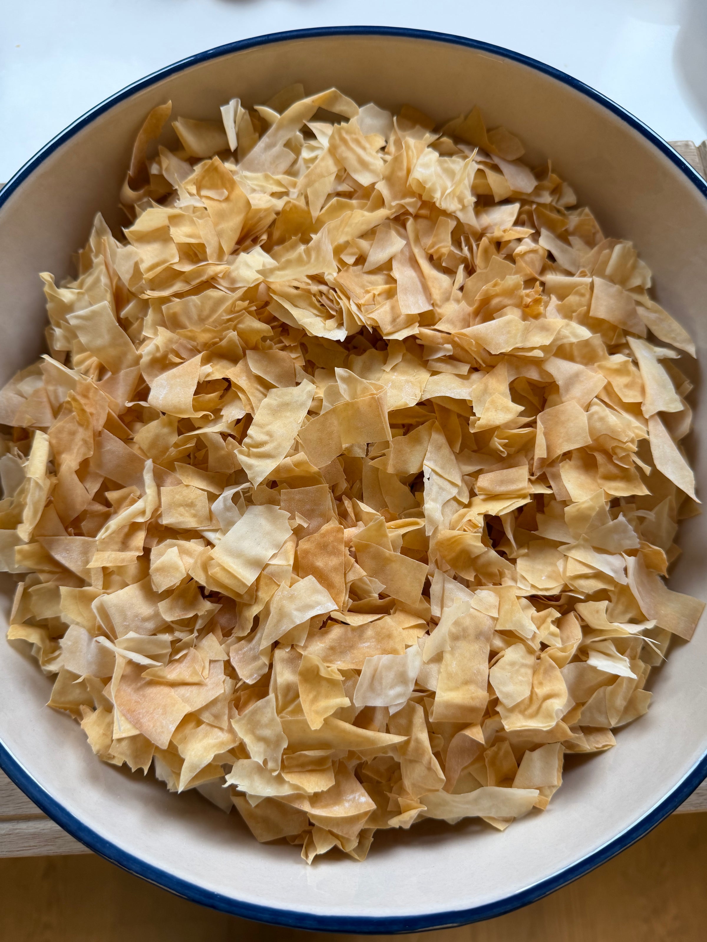 A bowl filled with small, irregularly cut, golden and light brown crispy pieces of baked phyllo dough.