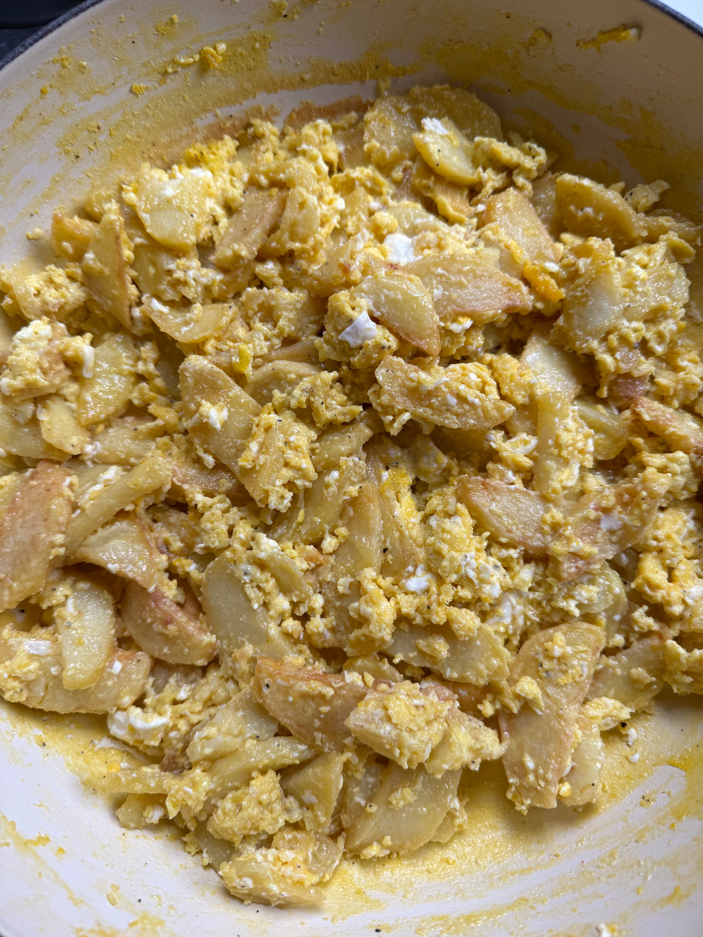 Scrambled eggs mixed with pan-fried potato slices in a skillet, creating a yellow and golden-colored, rustic-looking egg and potato dish.