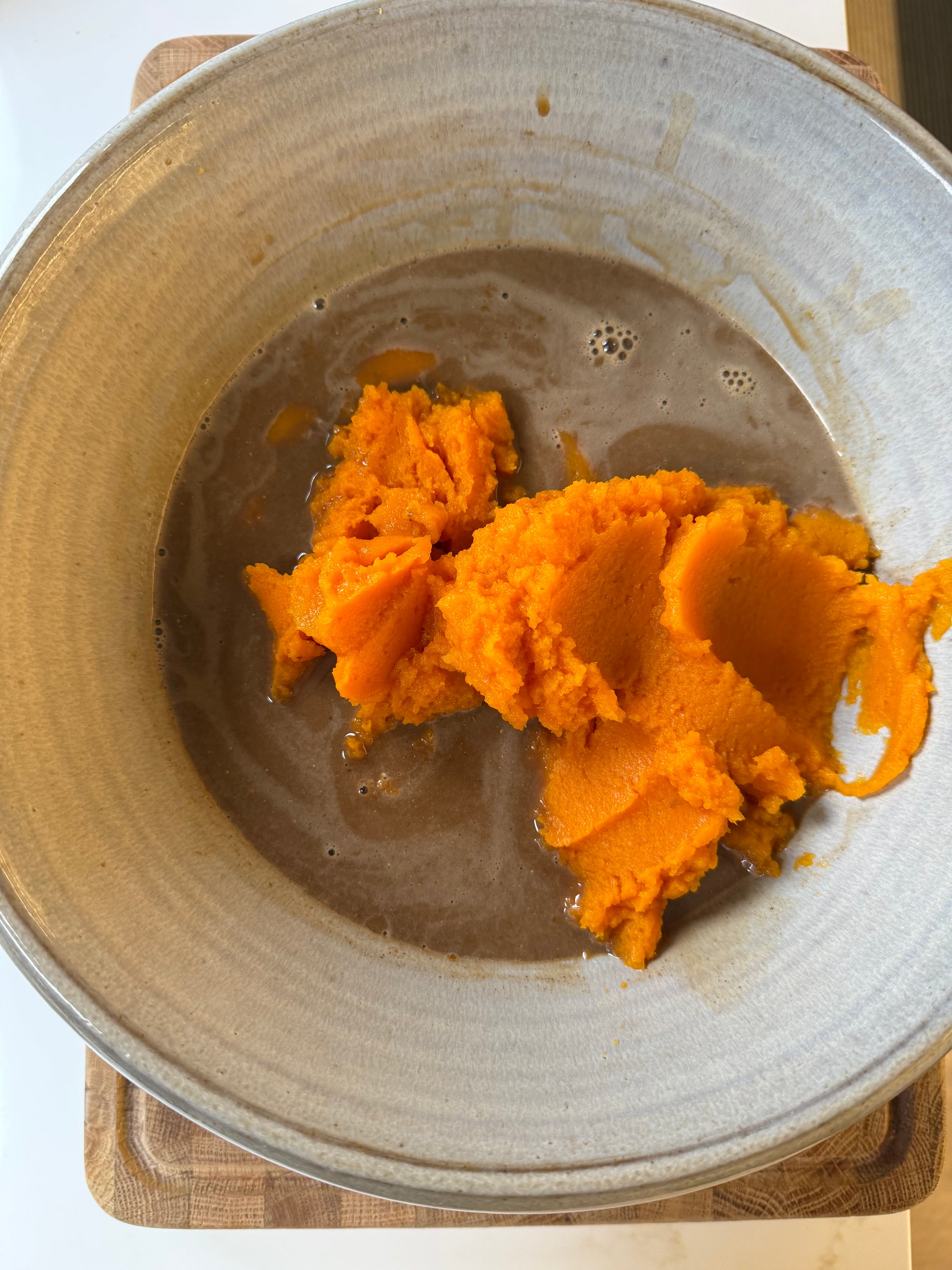 A dollop of bright orange pumpkin puree in a bowl of dark brown liquid.