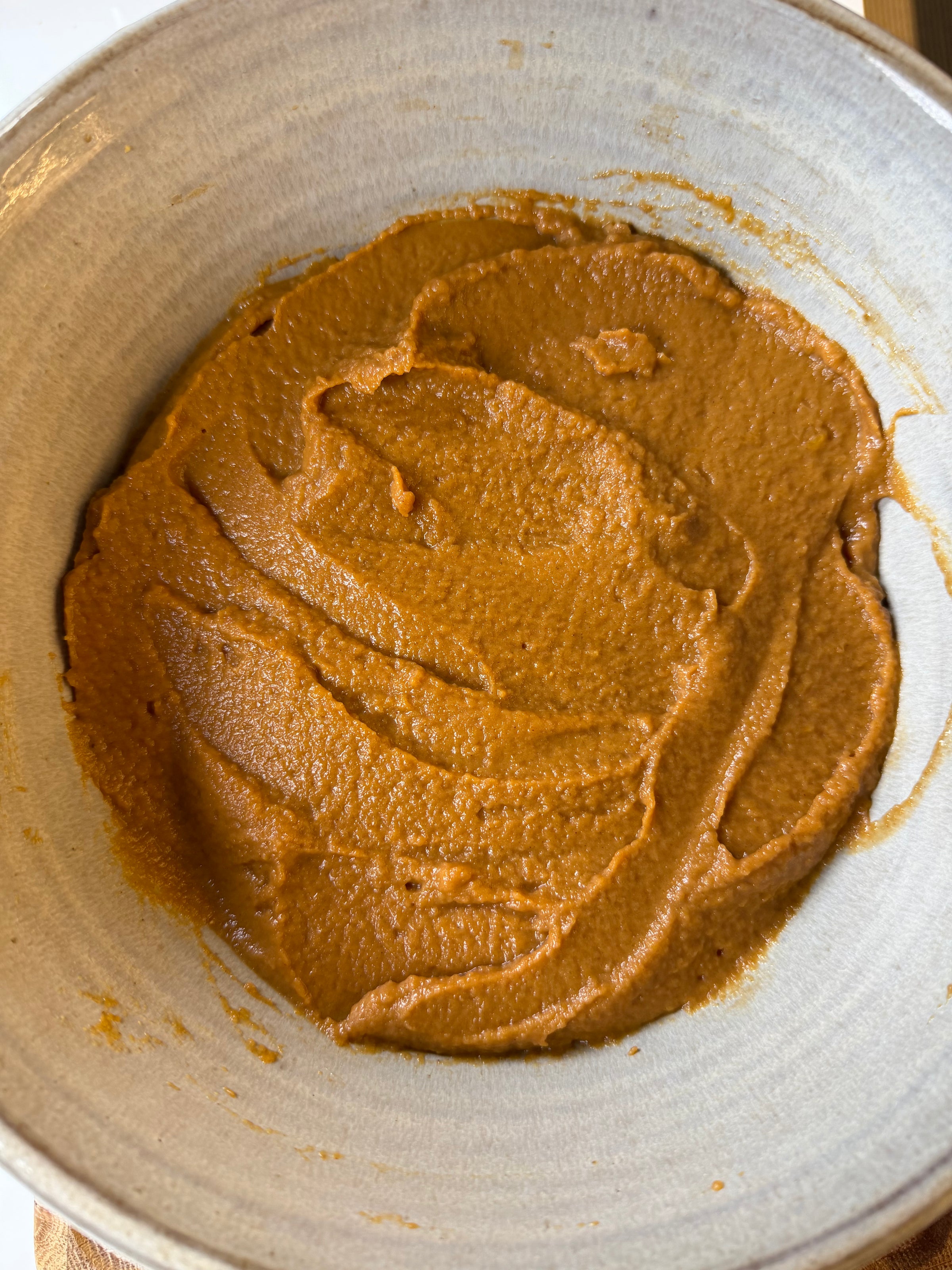 A bowl of smooth, orange pureed pumpkin.