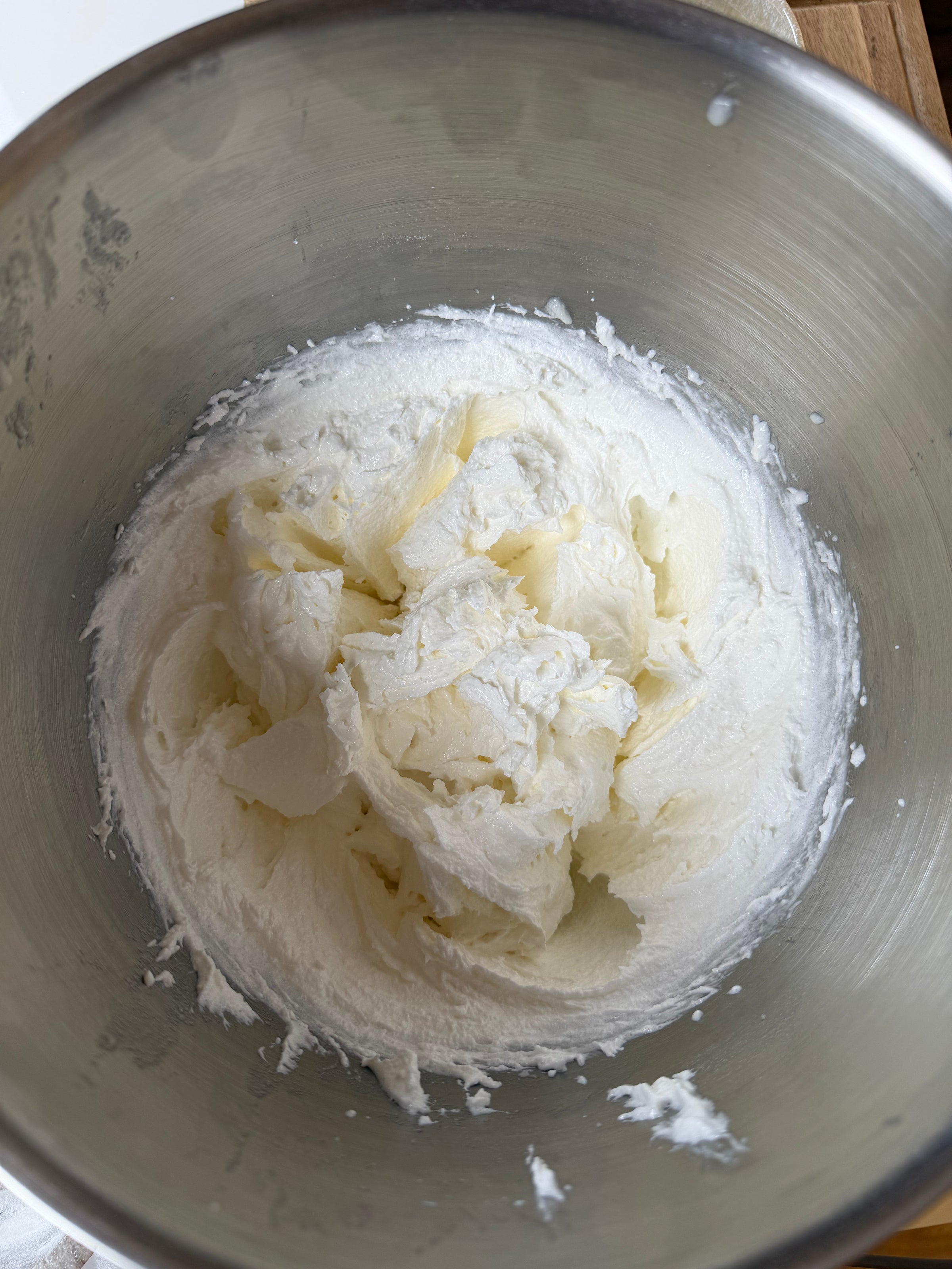 A stainless steel mixing bowl filled with creamy, whipped butter and sugar, ready to be mixed into a baking recipe.
