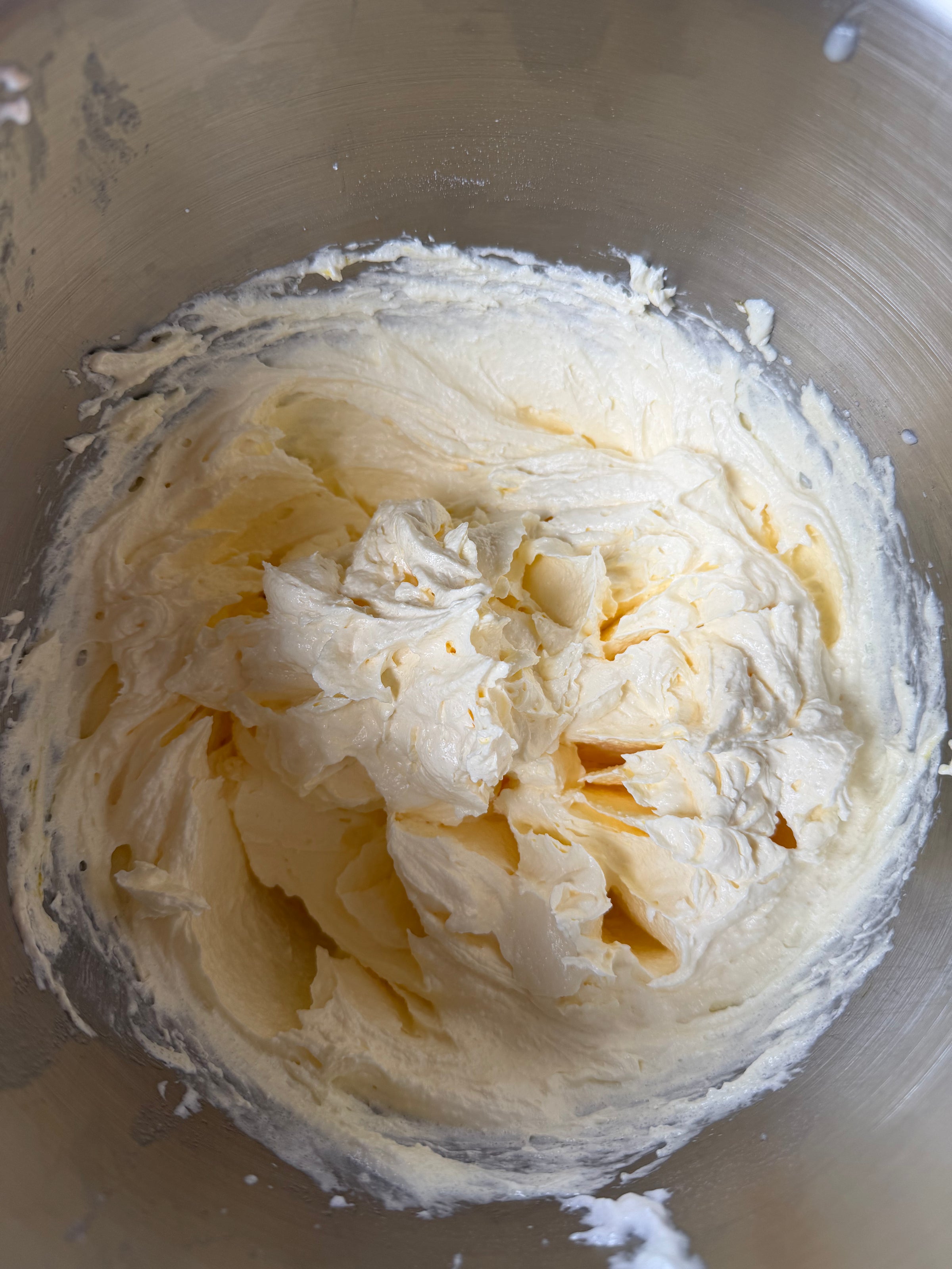 A close-up of creamy, whipped butter and sugar mixture in a metal mixing bowl, showing a smooth and fluffy texture.