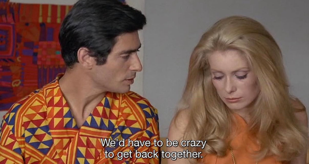 A man in a colorful shirt speaks to a woman in an orange dress, both looking serious. The subtitle reads, Wed have to be crazy to get back together..