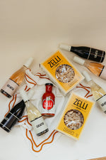 The Gratsi Wine & Pasta Holiday Bundle is displayed on a white cloth with orange trim, set against a beige background.
