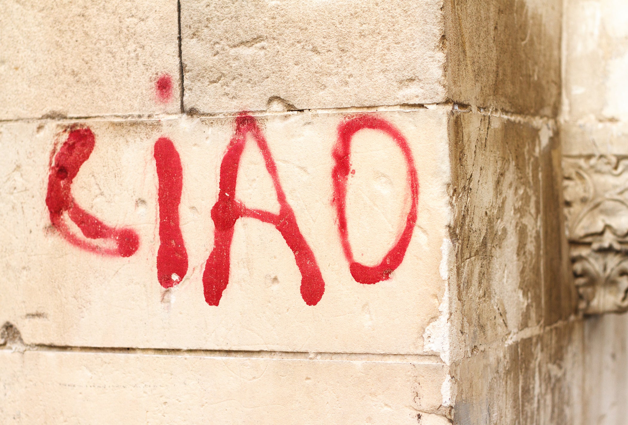 The word CIAO is spray-painted in red on a beige stone wall, with the paint appearing slightly drippy.