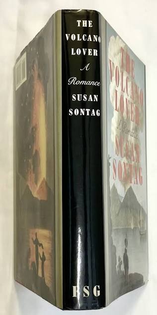 Front and spine view of the book The Volcano Lover: A Romance by Susan Sontag. The cover features an illustration of people watching a volcano erupt near water. The spine has the title and authors name in white letters.